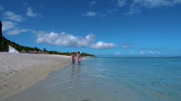 ル・モーンビーチモーリシャス、ヤシの木と白い砂の青い海のカップルの男性と女性が休暇中にビーチを歩く — ストック動画