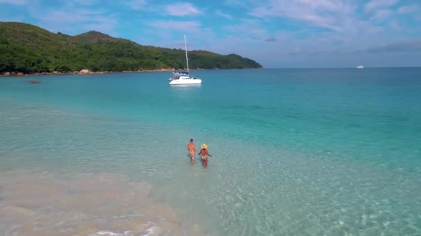 Praslin Seychelles tropical island with withe beaches and palm trees, couple men and women mid age on vacation at the Seychelles visiting the tropical beach of Anse Lazio Praslin Seychelles drone view — Vídeo de stock