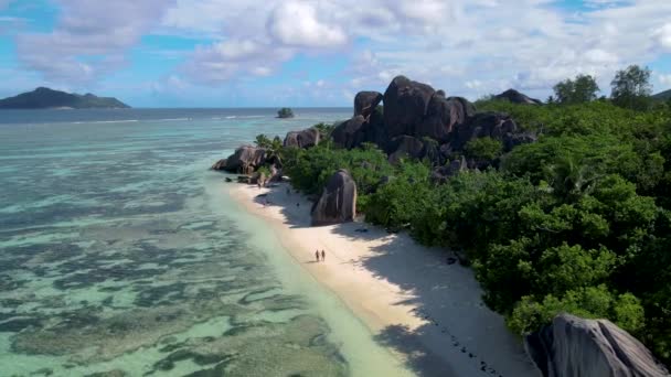 Anse Source dArgent beach, La Digue Island, Seyshelles, Drone légi kilátás a La Digue Seychelles madártávlatból, pár férfi és nő sétál a strandon napnyugtakor egy luxus nyaralás — Stock videók