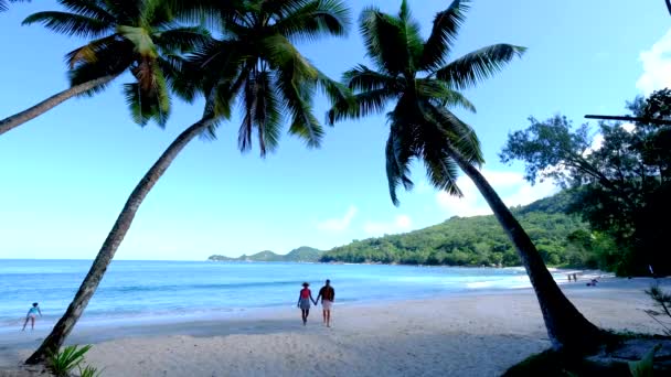 Anse Takamaka praia Mahe Seychelles, praia tropical com palmeiras e um oceano azul, casal homem e mulher na praia — Vídeo de Stock