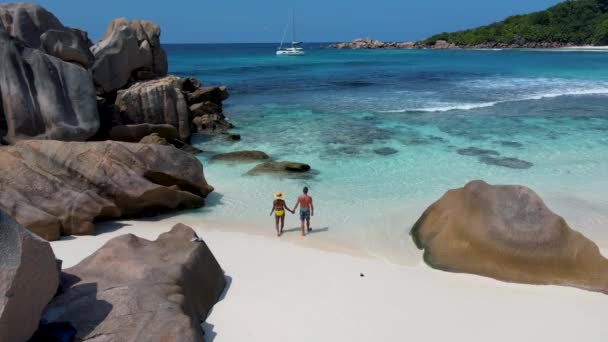 Playa de Anse Cocos, Isla La Digue, Seyshelles, vista aérea Drone de La Digue Seychelles vista de pájaro, pareja de hombres y mujeres caminando en la playa durante el atardecer en unas vacaciones de lujo — Vídeos de Stock