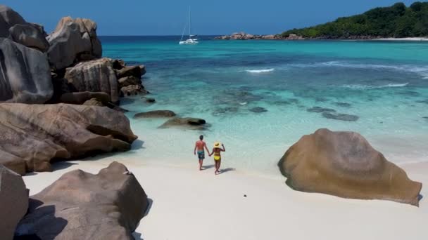 Praia de Anse Cocos, Ilha de La Digue, Seyshelles, Drone vista aérea de La Digue Seychelles vista para os olhos de pássaro, homens de casal e mulher andando na praia durante o pôr do sol em umas férias de luxo — Vídeo de Stock