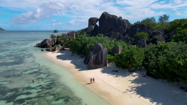 Anse Source dArgent beach, La Digue Island, Seyshelles, Drone légi kilátás a La Digue Seychelles madártávlatból, pár férfi és nő sétál a strandon napnyugtakor egy luxus nyaralás — Stock videók