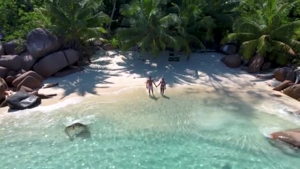 Praslin Seychelles tropical island with withe beaches and palm trees, couple men and women mid age on vacation at the Seychelles visiting the tropical beach of Anse Lazio Praslin Seychelles drone view — Vídeo de Stock