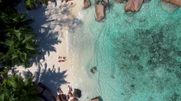 Praslin Seychelles tropical island with withe beaches and palm trees, couple men and women mid age on vacation at the Seychelles visiting the tropical beach of Anse Lazio Praslin Seychelles drone view — Stock video