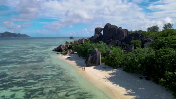 Anse Source Dargent beach, La Digue Island, Seyshelles, La Digueセイシェルのドローンの空の景色鳥の目の景色,豪華な休暇で日没時にビーチを歩くカップルの男性と女性 — ストック動画