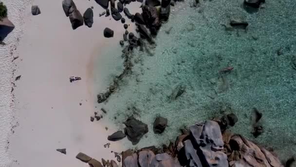 Anse Cocos plajı, La Digue Adası, Seyshelles, La Digue Seychelles kuş bakışı drone görüntüsü, günbatımında kumsalda yürüyen birkaç erkek ve kadın lüks bir tatilde. — Stok video