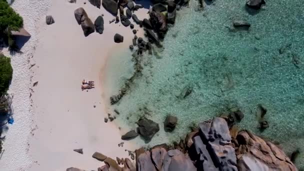 Anse Cocos παραλία, La Digue Island, Seyshelles, Drone εναέρια άποψη της La Digue Σεϋχέλλες πουλί θέα, ζευγάρι άνδρες και γυναίκες με τα πόδια στην παραλία κατά τη διάρκεια του ηλιοβασιλέματος σε πολυτελείς διακοπές — Αρχείο Βίντεο