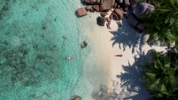 Praslin Seychellen tropische Insel mit weiten Stränden und Palmen, Paar Männer und Frauen mittleren Alters im Urlaub auf den Seychellen besuchen den tropischen Strand von Anse Lazio Praslin Seychellen Drohnenblick — Stockvideo