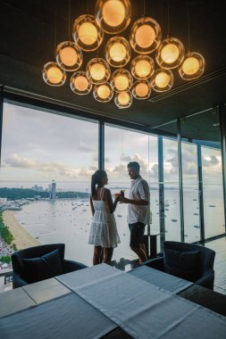 Gün batımında Hilton Sky Bar 'ın terasından görüntü. Tayland 'daki Pattaya çatı katı, çatıdaki bir bardan gün batımını izleyen çift.