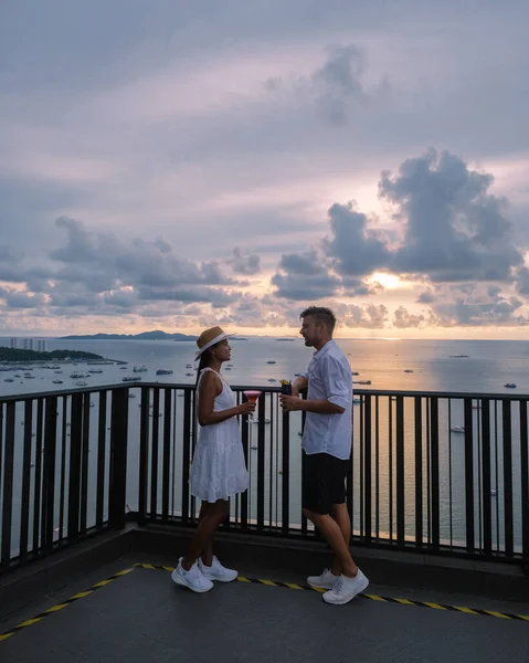 Vista desde la terraza del Hilton Sky Bar al atardecer. Pattaya bar en la azotea Tailandia, pareja de hombres y mujeres viendo la puesta de sol desde un bar en la azotea — Foto de Stock