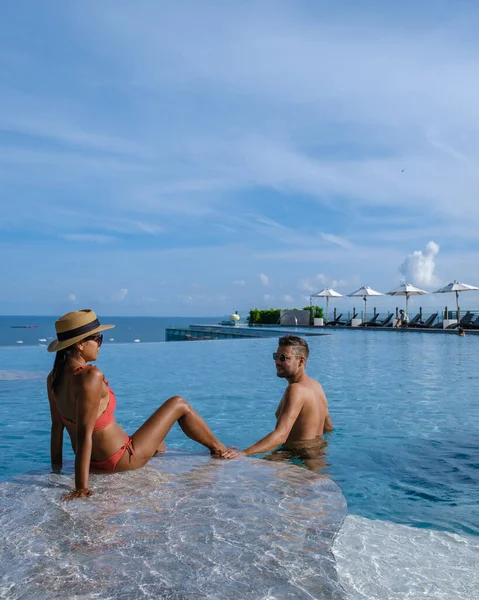 Pareja de hombres y mujeres en unas vacaciones de lujo disfrutando de la piscina infinita en la azotea, Pattaya Tailandia —  Fotos de Stock