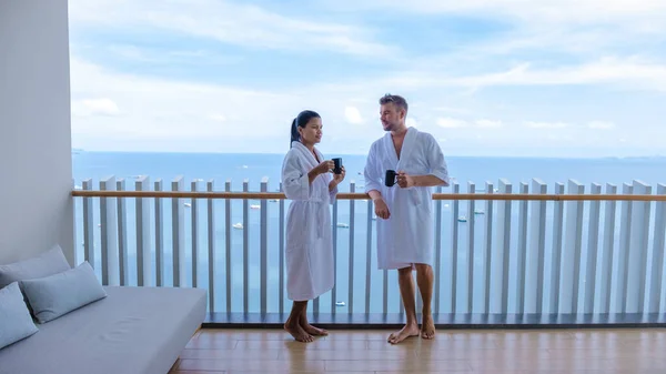 Couple men and woman having a coffee on the balcony looking out over the bay of Pattaya, Thai girl and European man on balcony of apartment condo in Thailand — Φωτογραφία Αρχείου