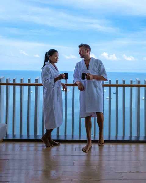 Couple men and woman having a coffee on the balcony looking out over the bay of Pattaya, Thai girl and European man on balcony of apartment condo in Thailand — Stockfoto