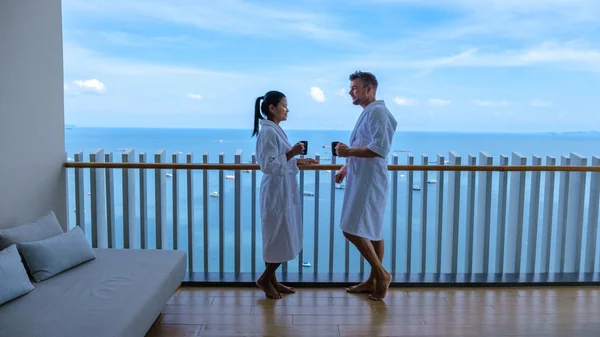 Pareja de hombres y mujeres tomando un café en el balcón con vistas a la bahía de Pattaya, chica tailandesa y hombre europeo en el balcón del apartamento condominio en Tailandia —  Fotos de Stock
