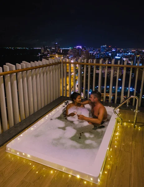 Paar mannen en vrouwen op een balkon in bad met uitzicht over de baai van Pattaya Thailand, mannen en vrouwen in een jacuzzi. — Stockfoto