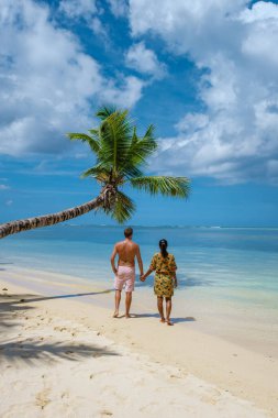 Mahe Seyşeller, Mahe Seyşeller sahilinde palmiye ağaçları ve mavi okyanuslu tropikal plaj. Seyşeller 'de tatilde olan çift ve kadın.