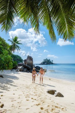 Mahe Seyşeller, Mahe Seyşeller sahilinde palmiye ağaçları ve mavi okyanuslu tropikal plaj. Seyşeller 'de tatilde olan çift ve kadın.