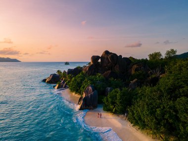 Anse Source dArgent, La Digue Seychelles, Seyşeller 'de lüks bir tatil sırasında tropik bir plajda yaşayan genç bir çift. Tropik sahil Anse Kaynak dArgent, La Digue Seyşeller