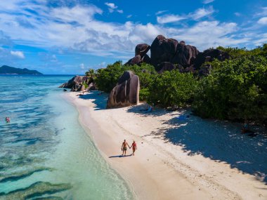 Anse Source dArgent, La Digue Seychelles, Seyşeller 'de lüks bir tatil sırasında tropik bir plajda yaşayan genç bir çift. Tropik sahil Anse Kaynak dArgent, La Digue Seyşeller