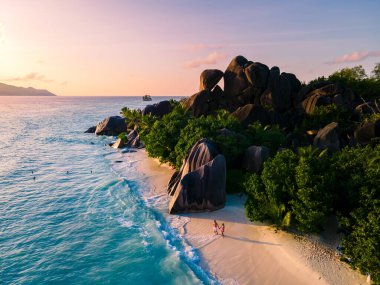 Anse Source dArgent, La Digue Seychelles, Seyşeller 'de lüks bir tatil sırasında tropik bir plajda yaşayan genç bir çift. Tropik sahil Anse Kaynak dArgent, La Digue Seyşeller