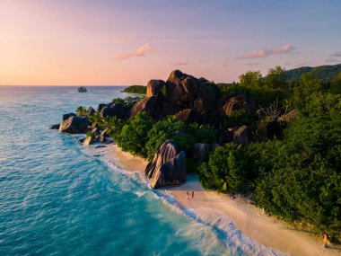 Anse Source dArgent, La Digue Seychelles, Seyşeller 'de lüks bir tatil sırasında tropik bir plajda yaşayan genç bir çift. Tropik sahil Anse Kaynak dArgent, La Digue Seyşeller