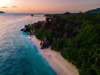 Anse Source dArgent, La Digue Seychelles, Seyşeller 'de lüks bir tatil sırasında tropik bir plajda yaşayan genç bir çift. Tropik sahil Anse Kaynak dArgent, La Digue Seyşeller