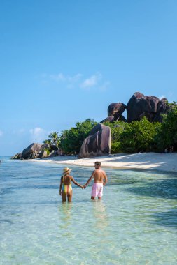 Anse Source dArgent, La Digue Seychelles, Seyşeller 'de lüks bir tatil sırasında tropik bir plajda yaşayan genç bir çift. Tropik sahil Anse Kaynak dArgent, La Digue Seyşeller