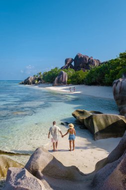 Anse Source dArgent, La Digue Seychelles, Seyşeller 'de lüks bir tatil sırasında tropik bir plajda yaşayan genç bir çift. Tropik sahil Anse Kaynak dArgent, La Digue Seyşeller
