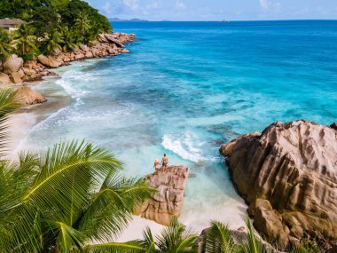 Anse Patates, La Digue Seychelles, young couple men and woman on a tropical beach during a luxury vacation in the Seychelles. Tropical beach Anse Patates, La Digue Seychelles