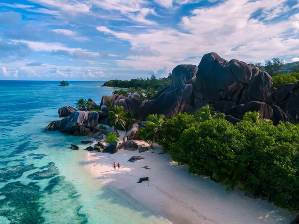Anse Source dArgent, La Digue Seychelles, Seyşeller 'de lüks bir tatil sırasında tropik bir plajda yaşayan genç bir çift. Tropik sahil Anse Kaynak dArgent, La Digue Seyşeller