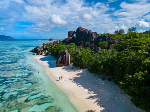 Anse Source dArgent, La Digue Seychelles, Seyşeller 'de lüks bir tatil sırasında tropik bir plajda yaşayan genç bir çift. Tropik sahil Anse Kaynak dArgent, La Digue Seyşeller
