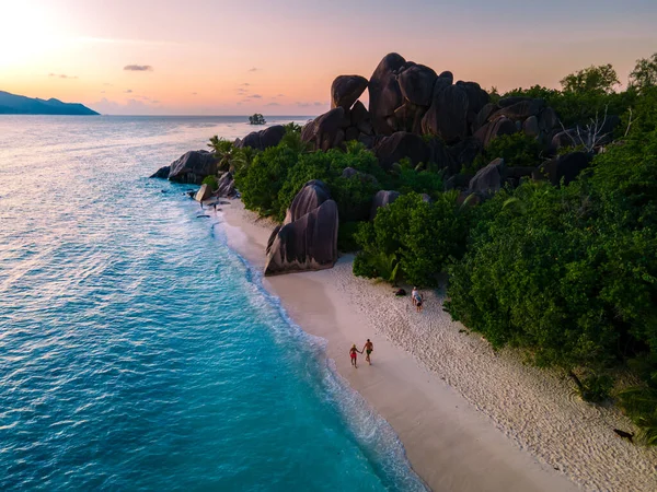 Anse Source dArgent, La Digue Seychelles, Seyşeller 'de lüks bir tatil sırasında tropik bir plajda yaşayan genç bir çift. Tropik sahil Anse Kaynak dArgent, La Digue Seyşeller