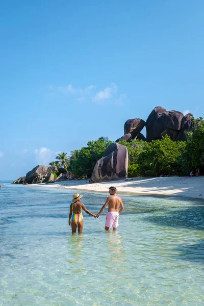 Anse Source dArgent, La Digue Seychelles, Seyşeller 'de lüks bir tatil sırasında tropik bir plajda yaşayan genç bir çift. Tropik sahil Anse Kaynak dArgent, La Digue Seyşeller