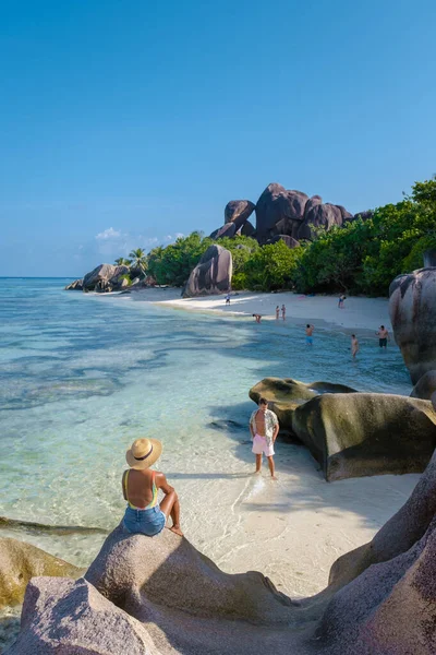 Anse Source dArgent, La Digue Seychelles, Seyşeller 'de lüks bir tatil sırasında tropik bir plajda yaşayan genç bir çift. Tropik sahil Anse Kaynak dArgent, La Digue Seyşeller