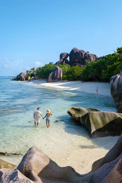 Anse Source dArgent, La Digue Seychelles, Seyşeller 'de lüks bir tatil sırasında tropik bir plajda yaşayan genç bir çift. Tropik sahil Anse Kaynak dArgent, La Digue Seyşeller