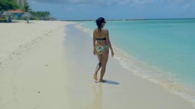 Sahilde dinlenen bir kadın, Palm Beach Aruba Karayipleri, Aruba 'da palmiye ağaçları olan beyaz kumlu plaj, sahilde bikinili Asyalı bir kadın.