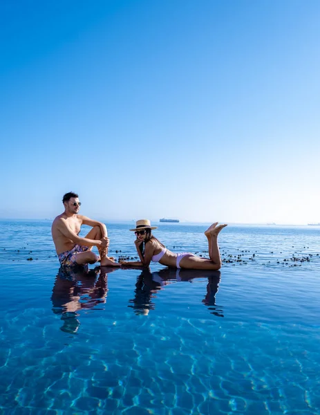 Coppia uomo e donna di fronte alla piscina Infinity affacciata sull'oceano di Città del Capo Sud Africa, uomo e donna in piscina durante il tramonto — Foto Stock