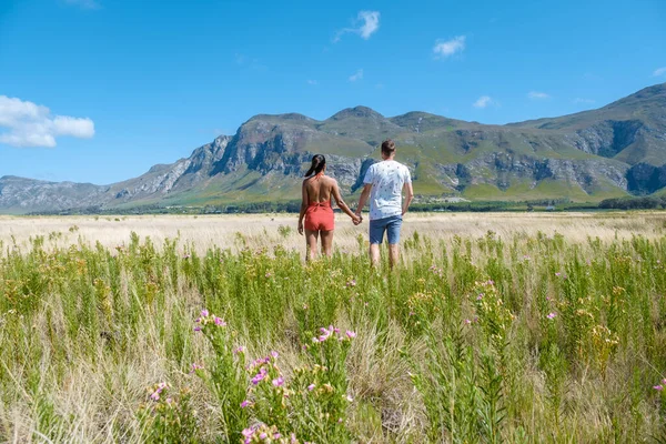 Man en vrouw in grasland tijdens vakantie in Zuid-Afrika, bergen en grasland in de buurt van Hermanus op de tuinroute West-Kaap Zuid-Afrika Walviskust — Stockfoto