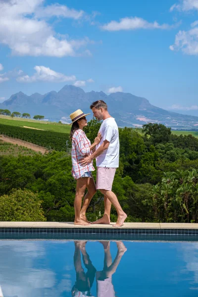 Ζευγάρι άνδρας και γυναίκα στην πισίνα με θέα στους αμπελώνες και τα βουνά του Stellenbosch Νότια Αφρική — Φωτογραφία Αρχείου