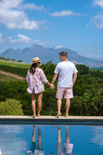 Pareja de hombres y mujeres en la piscina con vistas a los viñedos y montañas de Stellenbosch Sudáfrica —  Fotos de Stock