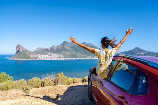 Mujer fuera de la ventana del coche viaje por carretera con las manos arriba, coche en Chapmans Peak Drive en Ciudad del Cabo Sudáfrica mirando hacia el océano —  Fotos de Stock