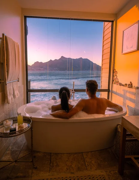 Hombre y mujer en bañera jaccuzi de vacaciones, pareja hombre y mujer en bañera con vistas al océano de Ciudad del Cabo Sudáfrica durante las vacaciones —  Fotos de Stock