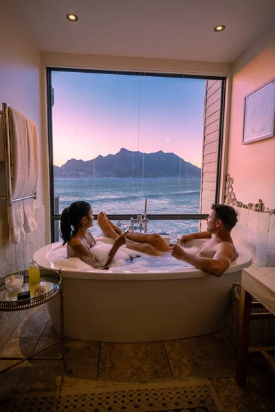 Man en vrouw in bad jaccuzi op vakantie, paar man en vrouw in bad kijken uit over de oceaan van Kaapstad Zuid-Afrika tijdens vakantie — Stockfoto