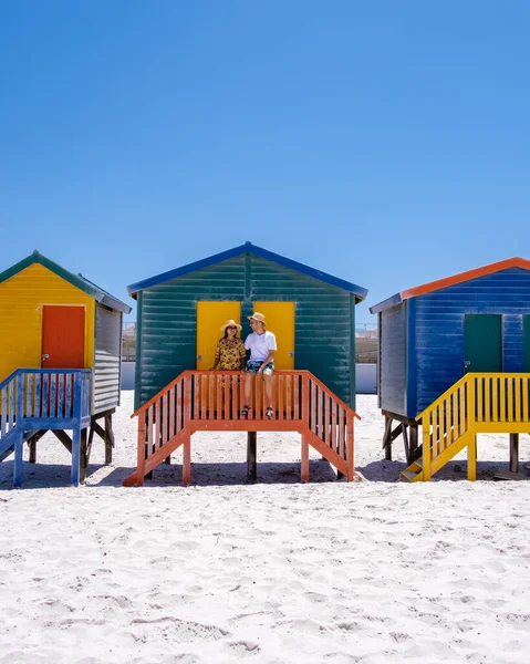 Pareja de hombres y mujeres visitando la playa de Muizenberg, colorida casa de playa en la playa de Muizenberg Ciudad del Cabo, cabañas de playa, Muizenberg, Ciudad del Cabo, False Bay, Sudáfrica — Foto de Stock