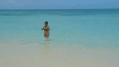 Sahilde dinlenen bir kadın, Palm Beach Aruba Karayipleri, Aruba 'da palmiye ağaçları olan beyaz kumlu plaj, sahilde bikinili Asyalı bir kadın.
