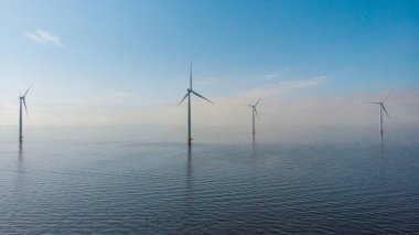 Huge windmill turbines, Offshore Windmill farm in the ocean Westermeerwind park , windmills isolated at sea on a beautiful bright day Netherlands Flevoland Noordoostpolder
