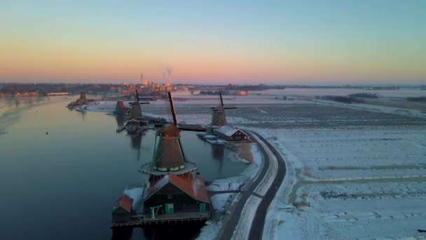 Houten windmolen in het Zaanse Schans windmolendorp in de winter met besneeuwd landschap, besneeuwde houten historische molens Zaanse Schans Nederland Holland — Stockvideo