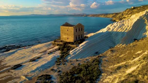 プンタ・ビアンカ、シチリア島のアグリジェント白い崖の上に放棄された石造りの家の古い遺跡と白いビーチ。シチリアイタリア,イタリアでの休暇中のカップル — ストック動画