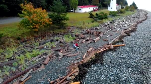 Острів Ванкувер (Канада) Старий історичний маяк на острові Кабо-Мадж пара в жовтому дощовому пальто під час шторму біля узбережжя. — стокове відео